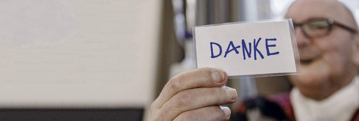 Ein Mann hält einen Zettel mit dem Wort Danke in die Kamera